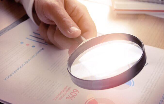 A person examining a document with a magnifying glass