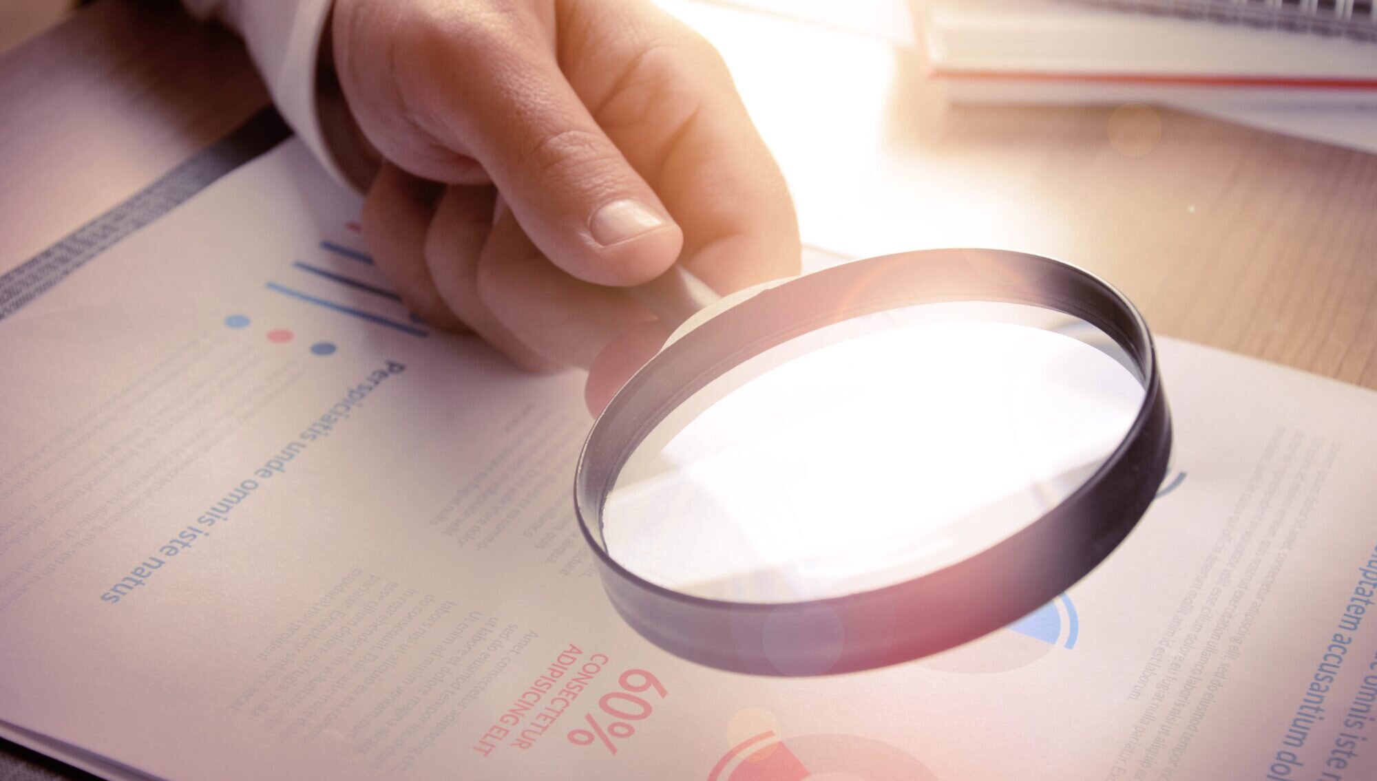 A person examining a document with a magnifying glass
