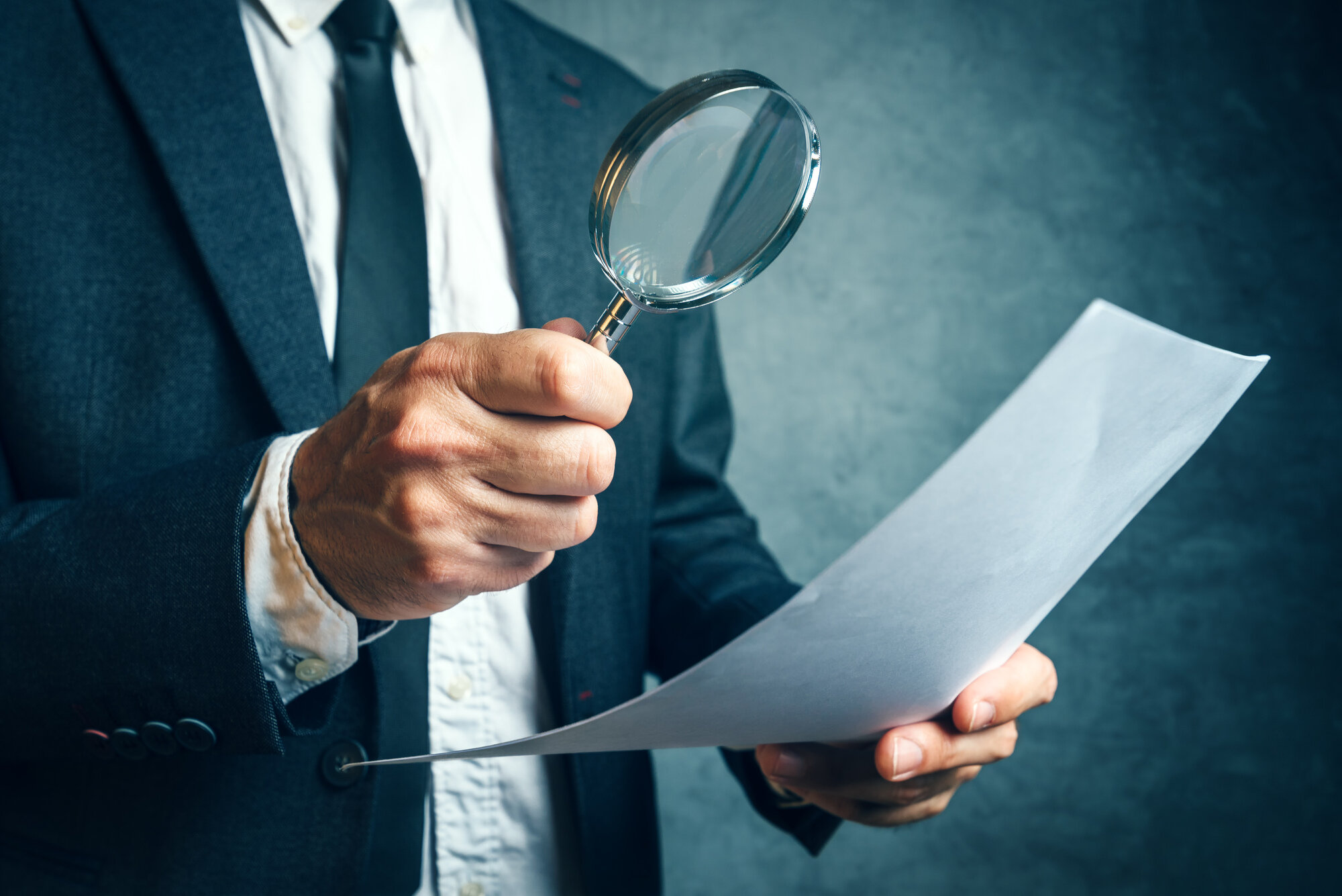 A person examining a document with a magnifying glass
