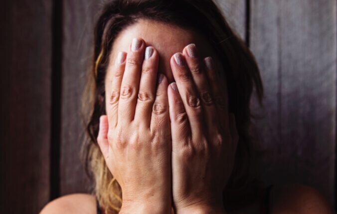 A woman covering her face with her hands