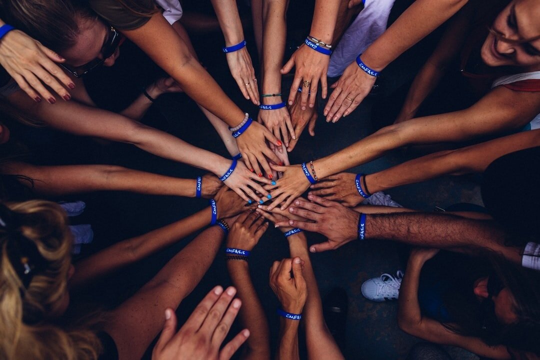 Hands of different skin tones joined together in the middle