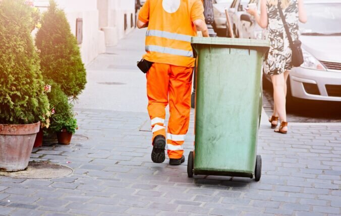 A bin man pulling a wheelie bin