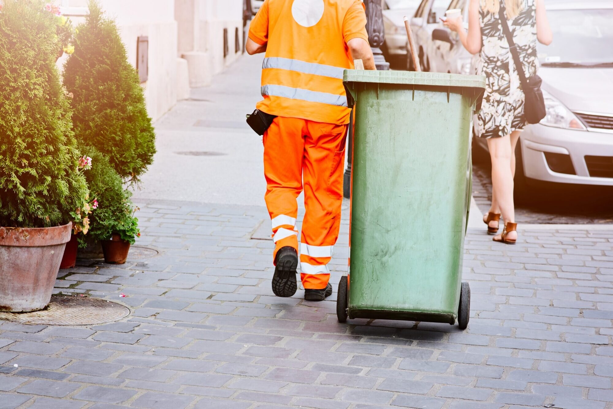 A bin man pulling a wheelie bin