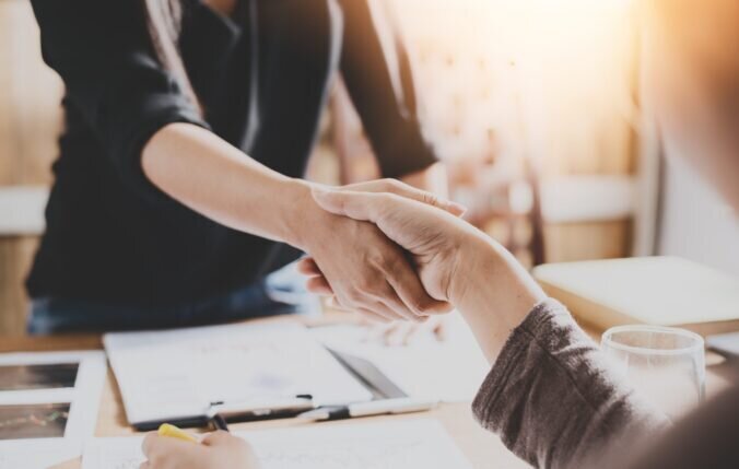 Two people shaking hands to close a deal