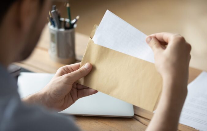 Close-up of someone's hands opening an envelope and taking out a piece of paper