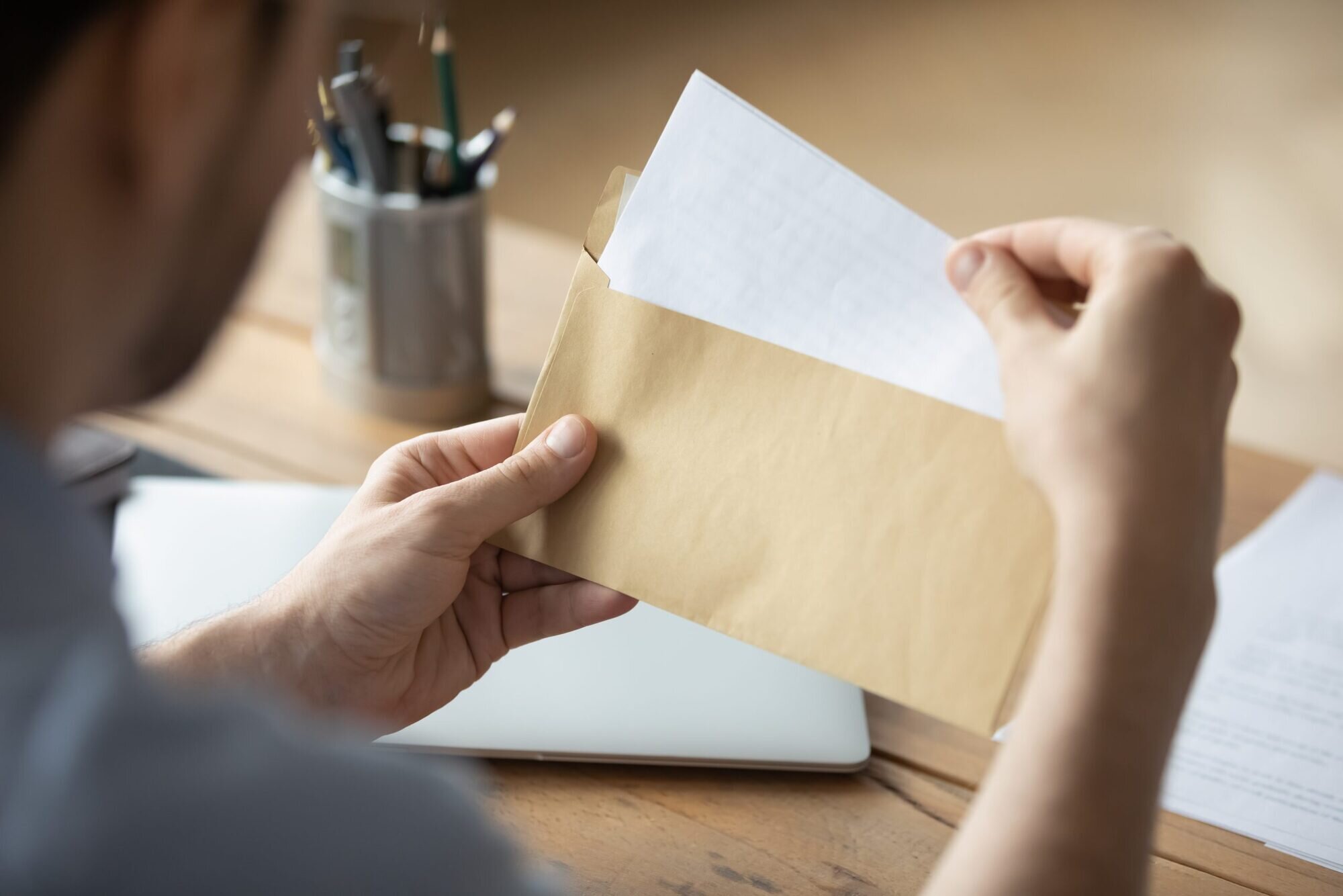 Close-up of someone's hands opening an envelope and taking out a piece of paper