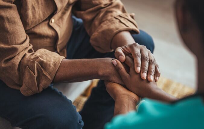 A person holding hands of another person in support