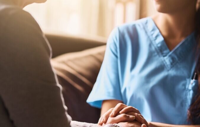 A nurse holding the hands of a patient in support
