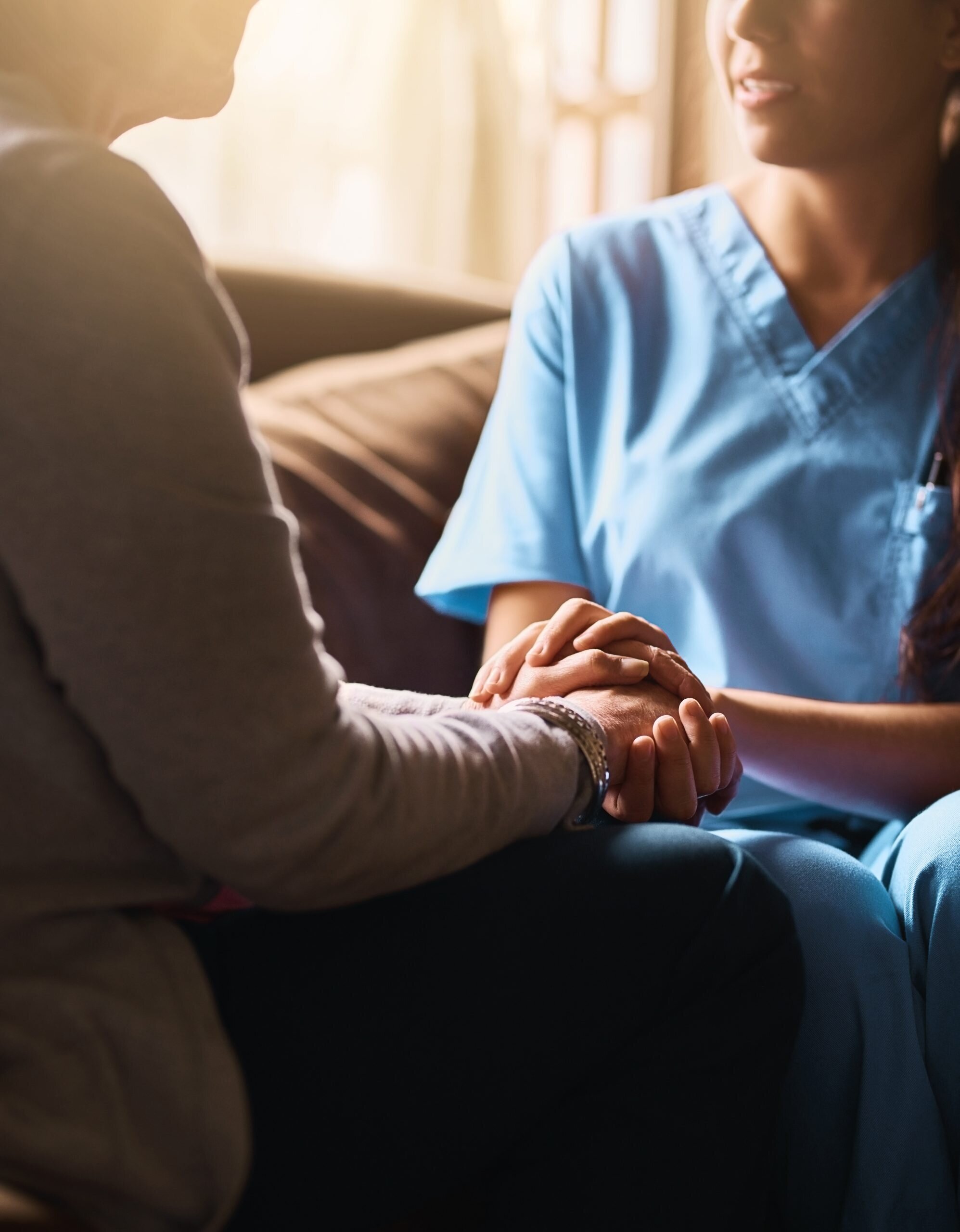 A nurse holding the hands of a patient in support