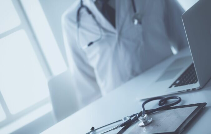 Doctor in uniform sitting by a desk with a stethoscope on it