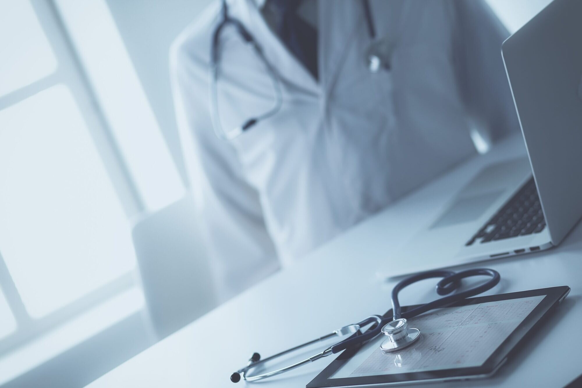 Doctor in uniform sitting by a desk with a stethoscope on it