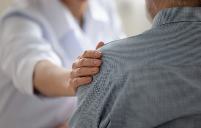 A doctor putting their hand on a patient's shoulder in support