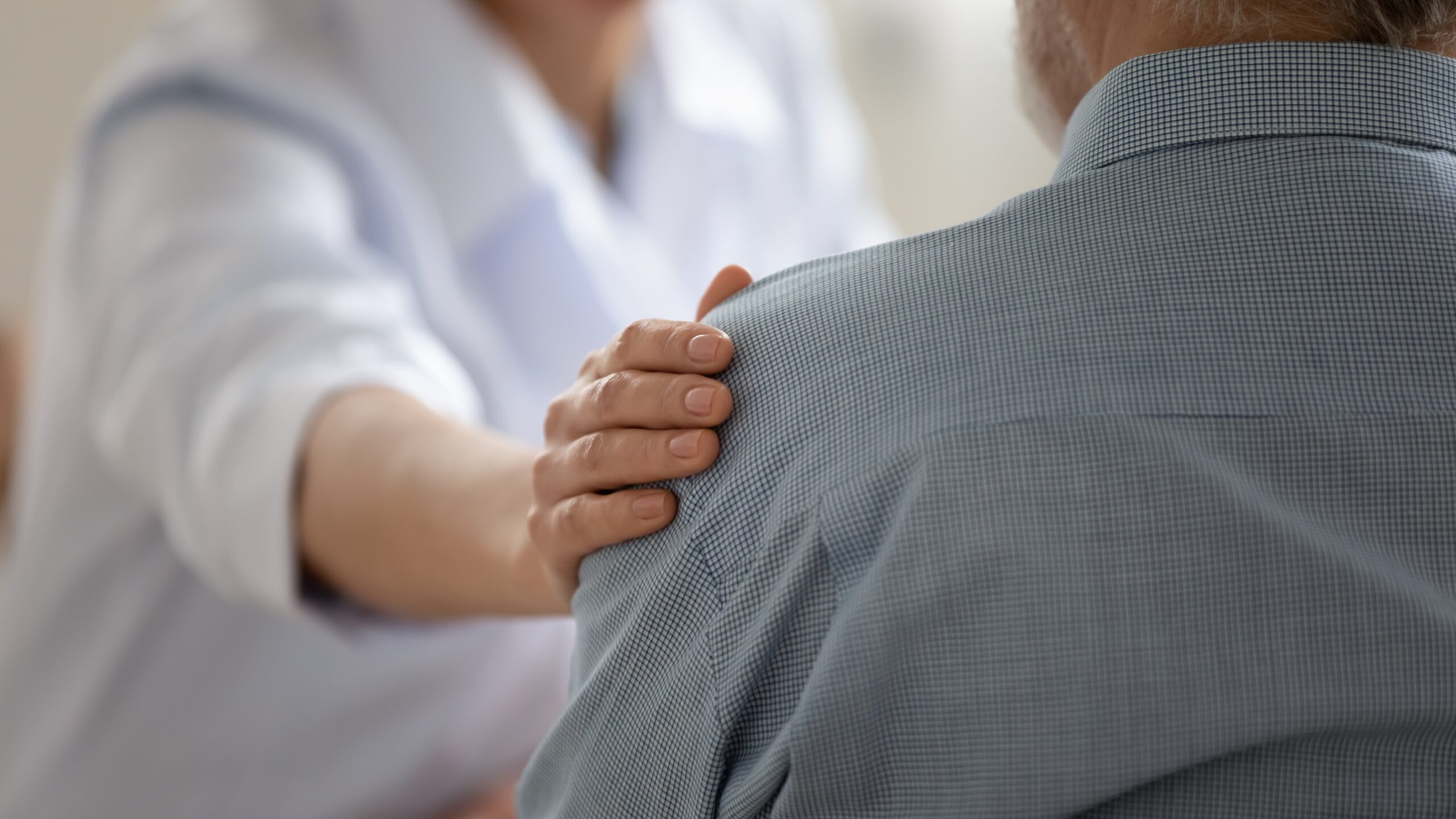 A doctor putting their hand on a patient's shoulder in support